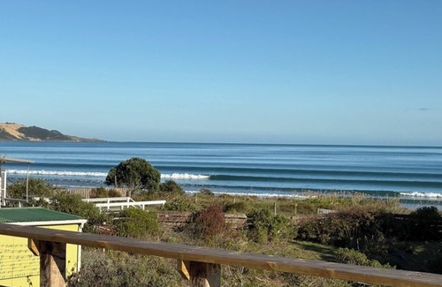 Ahipara Maison | Watch the waves from the large, sunny deck of this 1950's bach. Pet friendly.