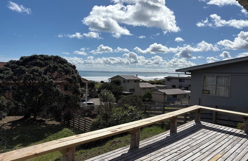 Ahipara Maison | Watch the waves from the large, sunny deck of this 1950's bach. Pet friendly.