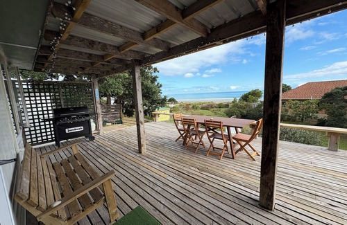 Ahipara Maison | Watch the waves from the large, sunny deck of this 1950's bach. Pet friendly.