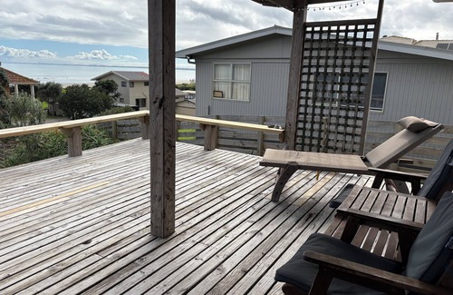Ahipara Maison | Watch the waves from the large, sunny deck of this 1950's bach. Pet friendly.