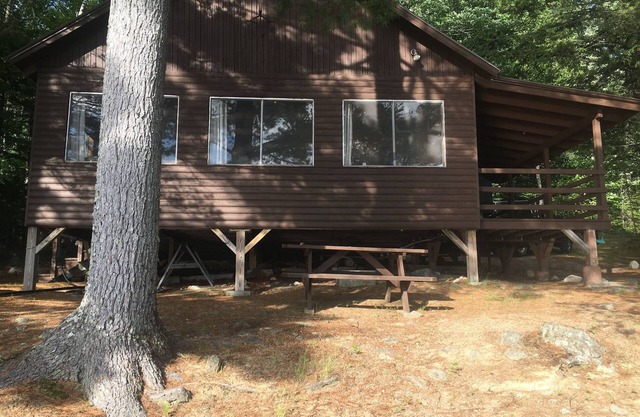Cabane rustique sur le lac Ambajejus avec plage de sable et vue sur la montagne