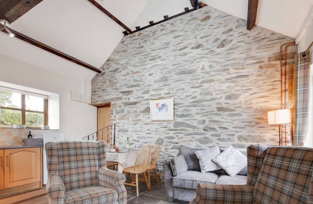 Belle conversion de grange avec des caractéristiques de caractère telles que des murs en pierres apparentes, des poutres en bois et des ardoises