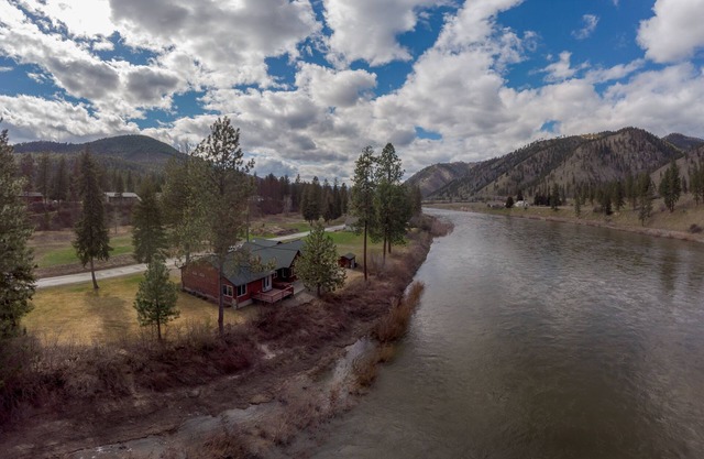 Belle cabine nichée à droite sur la rivière Clark Fork entourée de montagnes.