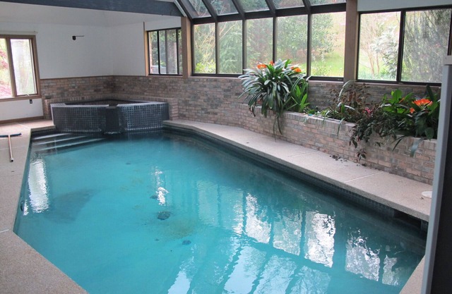 Piscine intérieure et spa dans une maison française contemporaine isolée dans les bois environnants