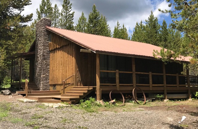 Cabine bordée de porche nichée dans les pins pour les jours d'été paresseux
