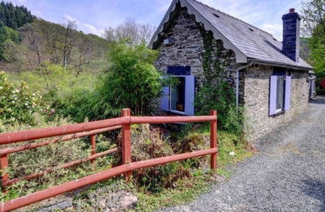Cette jolie maison en pierre est située au-dessus de la rivière Dulas, entourée par les collines boisées de la
