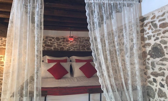 Asklipiio Maison | Traditional stone built single room house with traditional bed.