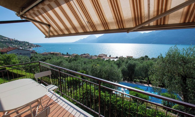 Assenza Appartement | balcon magnifique sur le lac avec une belle piscine et le jardin au milieu de palmiers et d'oliviers